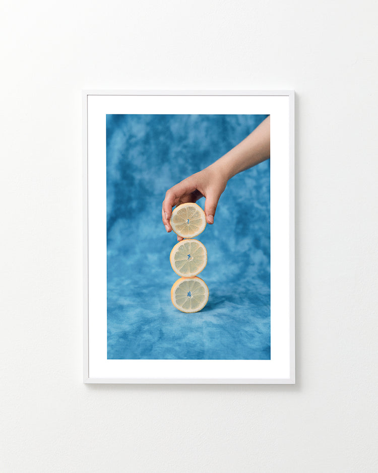 Three slices of freshly cut lemon on top of each other on a blue background.