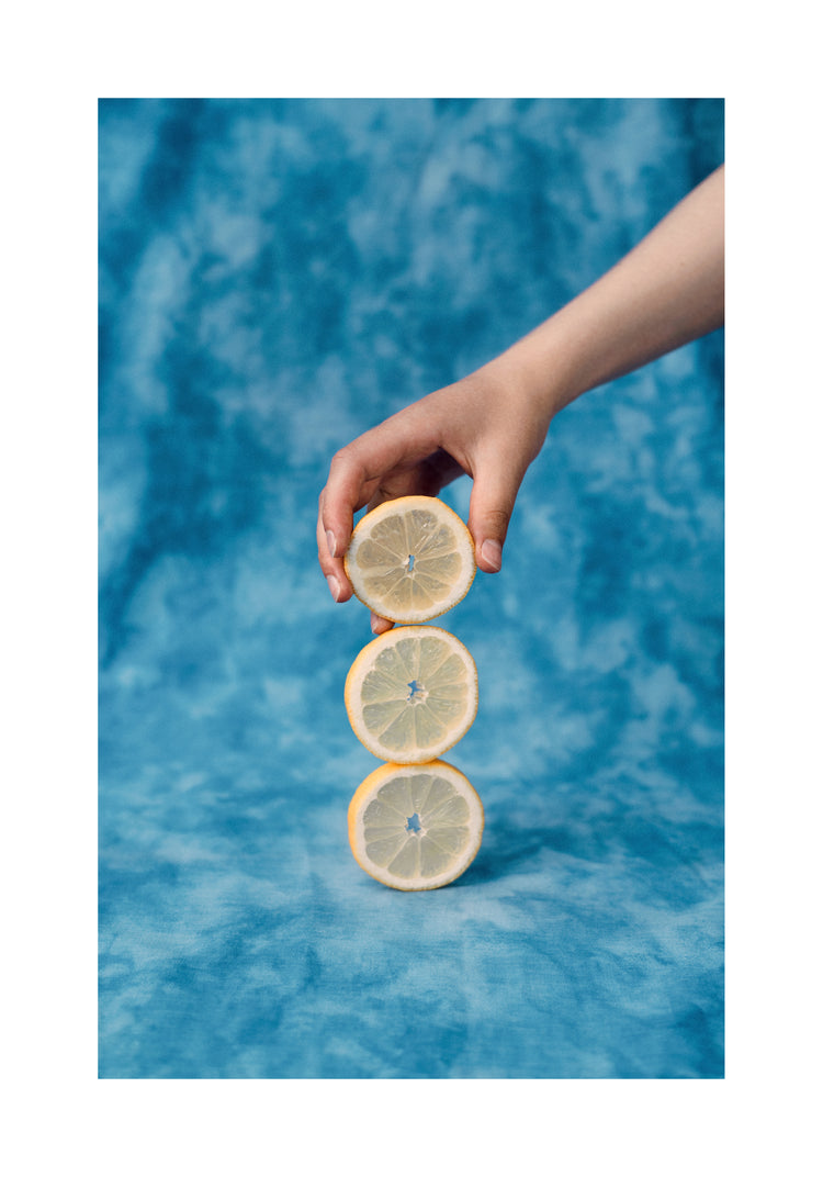 Three slices of freshly cut lemon on top of each other on a blue background.