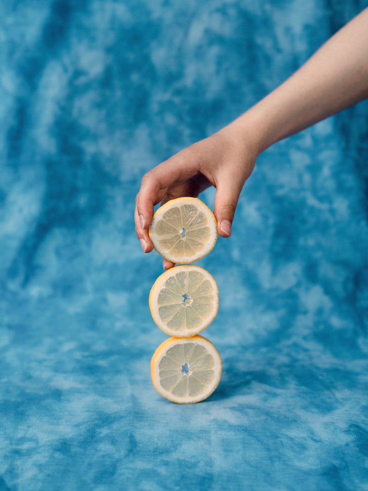 Three slices of freshly cut lemon on top of each other on a blue background.