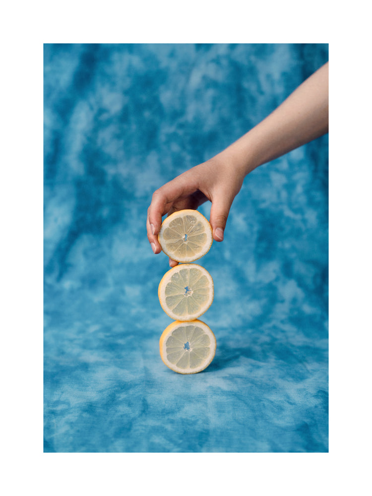 Three slices of freshly cut lemon on top of each other on a blue background.