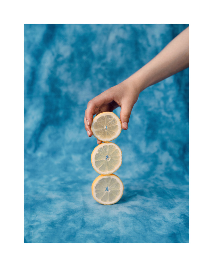Three slices of freshly cut lemon on top of each other on a blue background.