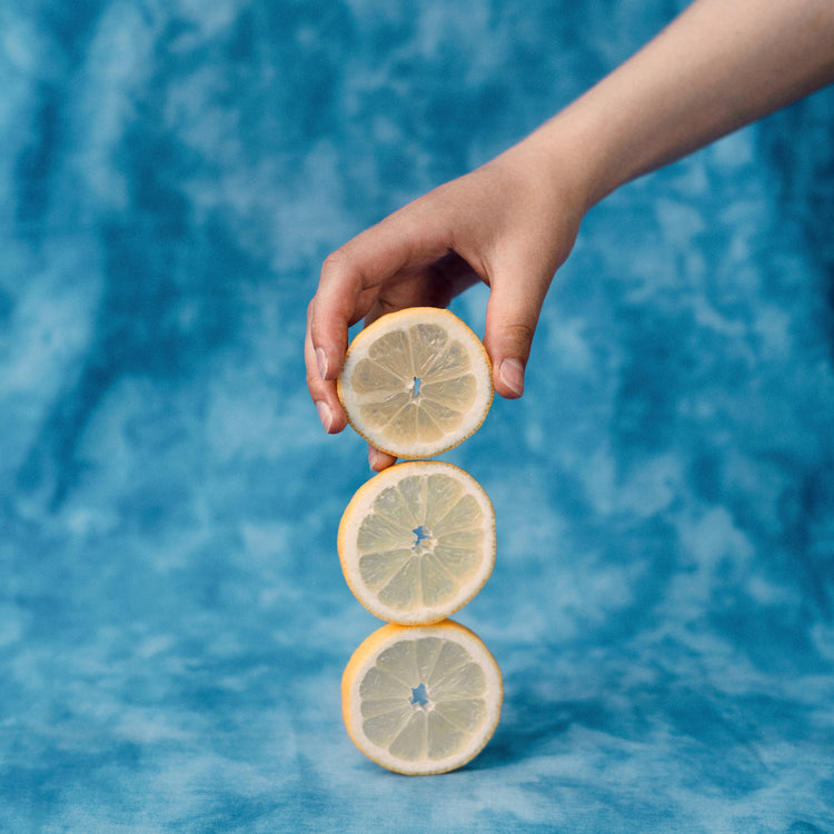 Three slices of freshly cut lemon on top of each other on a blue background.