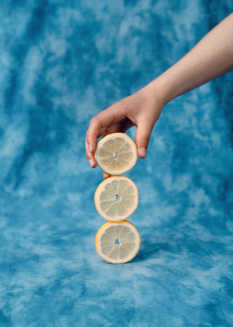 Three slices of freshly cut lemon on top of each other on a blue background.