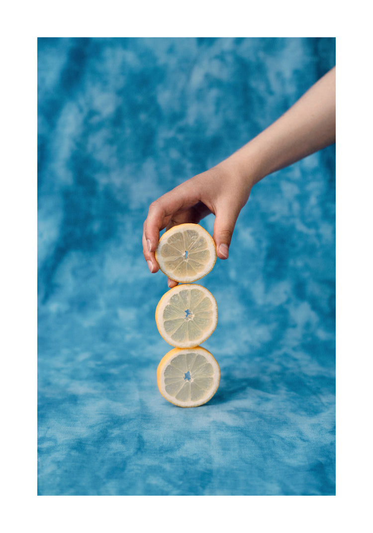 Three slices of freshly cut lemon on top of each other on a blue background.