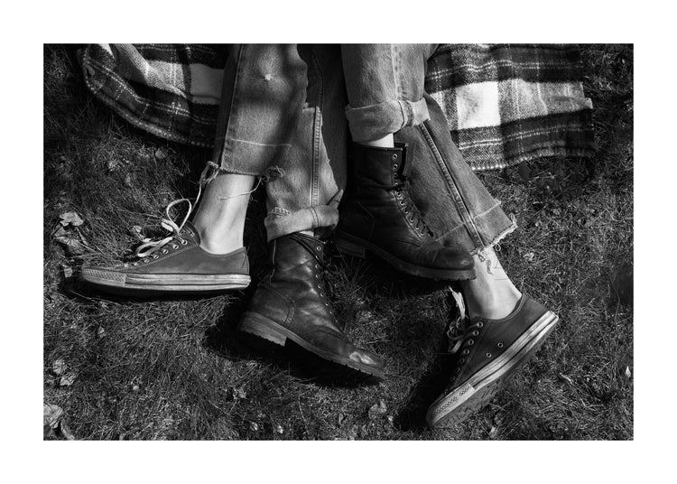 The entangled feet of a couple lying down on a picnic blanket.