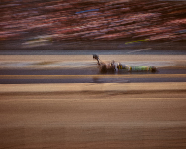 Blurry image of a cast going fast on a race car track.