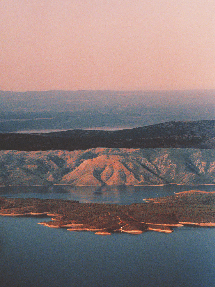 Landscape scenery with mountains and forests and lakes under crimson sky.