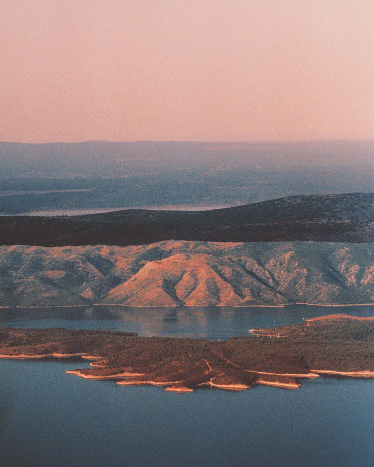 Landscape scenery with mountains and forests and lakes under crimson sky.