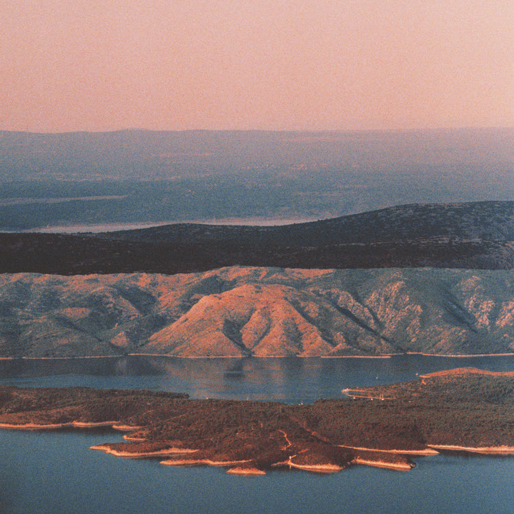 Landscape scenery with mountains and forests and lakes under crimson sky.