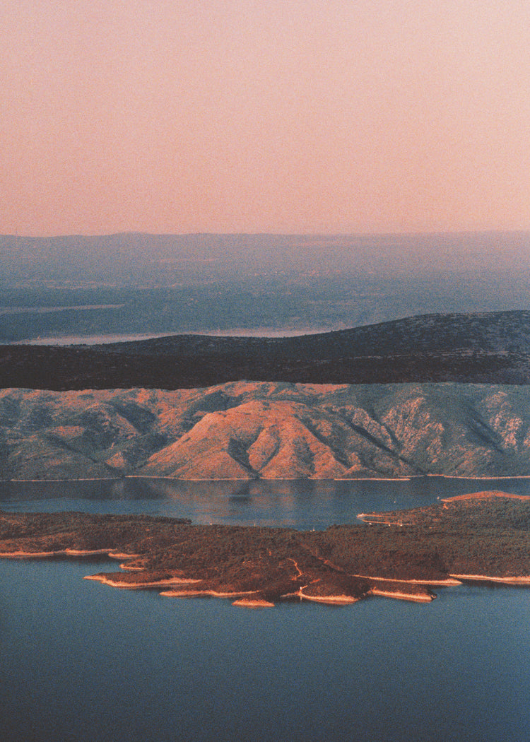 Landscape scenery with mountains and forests and lakes under crimson sky.