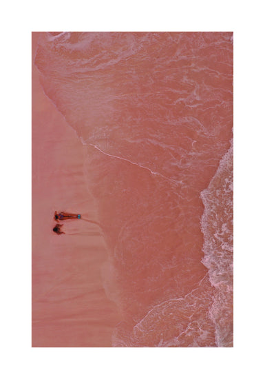Pink beach with a woman and a child sitting on the shore.