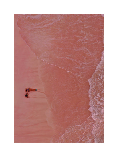 Pink beach with a woman and a child sitting on the shore.