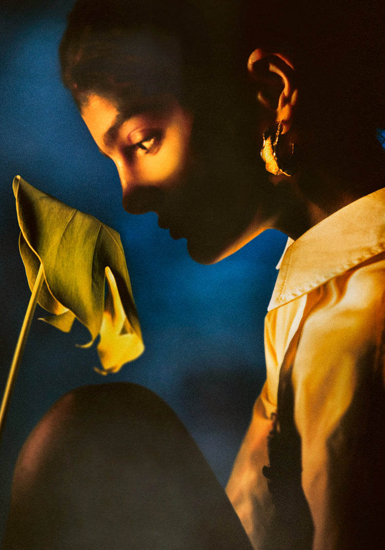 Woman staring into a leaf in front of a blue background.