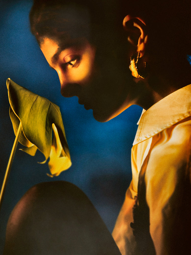 Woman staring into a leaf in front of a blue background.
