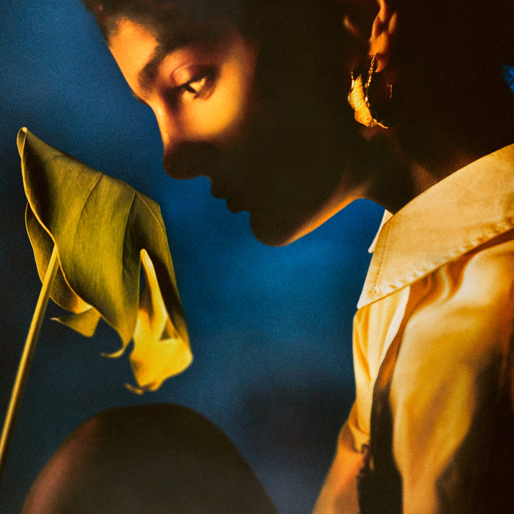 Woman staring into a leaf in front of a blue background.