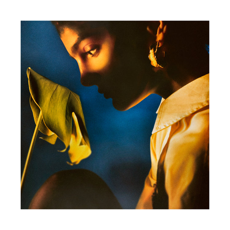 Woman staring into a leaf in front of a blue background.