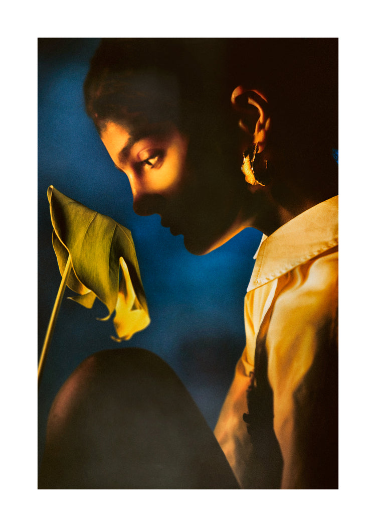 Woman staring into a leaf in front of a blue background.