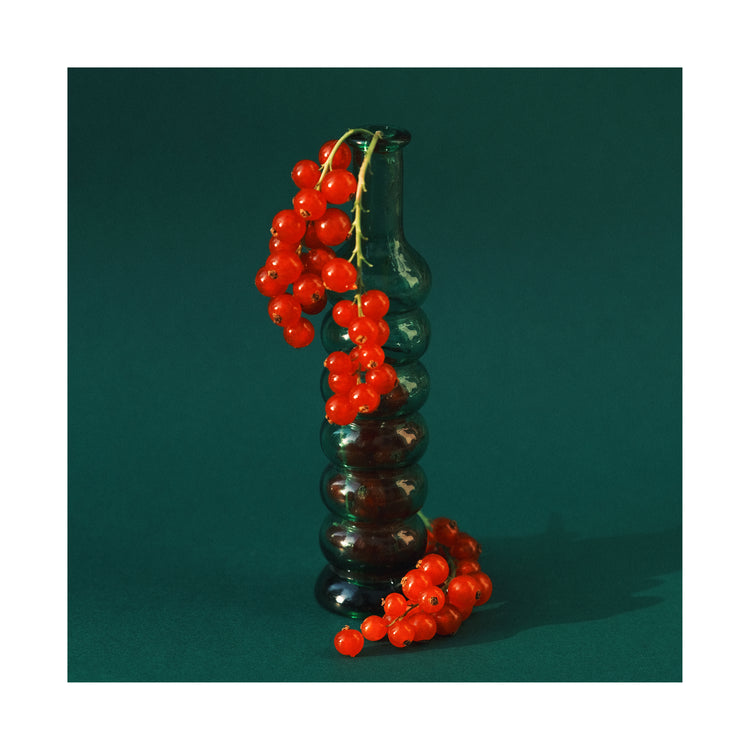 Green glass vase filled with redcurrant berries.