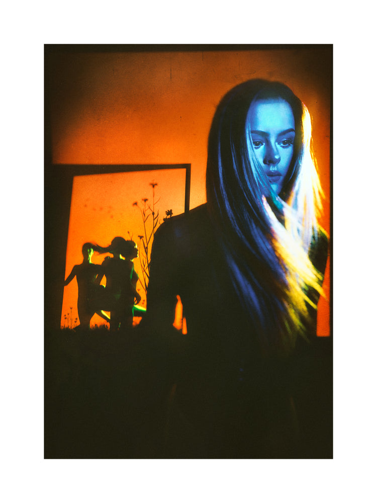 Woman with blonde hair and blue face standing in front of an orange wall.