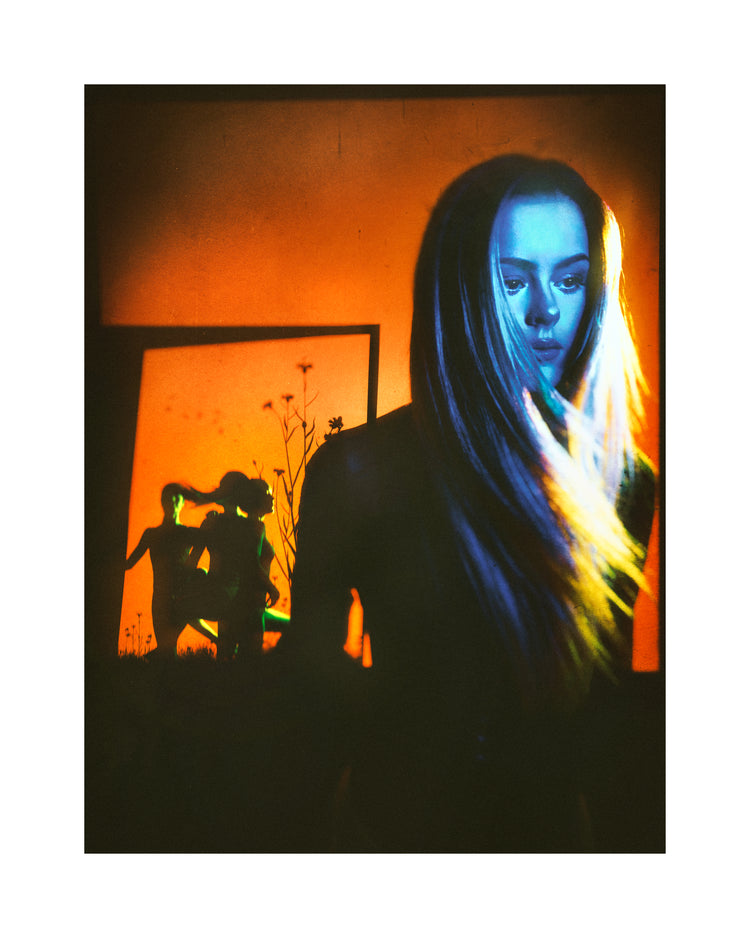 Woman with blonde hair and blue face standing in front of an orange wall.