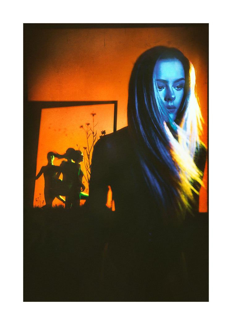 Woman with blonde hair and blue face standing in front of an orange wall.
