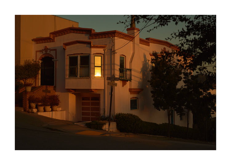 Suburban house laying at an intersection photographed during sunset.
