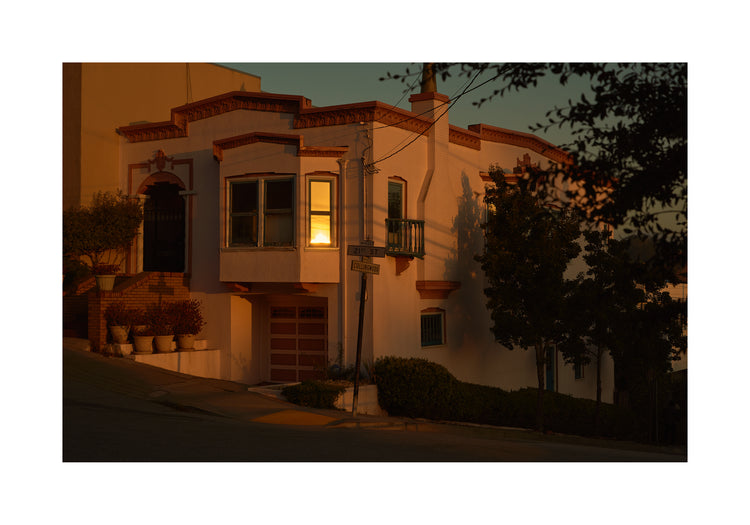 Suburban house laying at an intersection photographed during sunset.