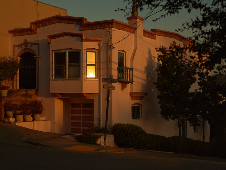 Suburban house laying at an intersection photographed during sunset.