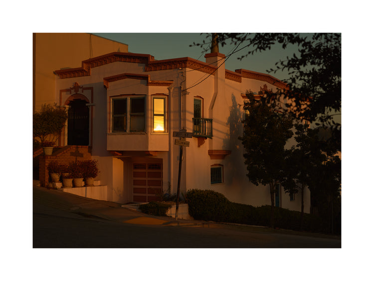 Suburban house laying at an intersection photographed during sunset.