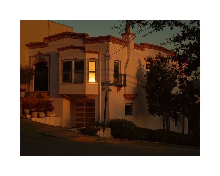 Suburban house laying at an intersection photographed during sunset.