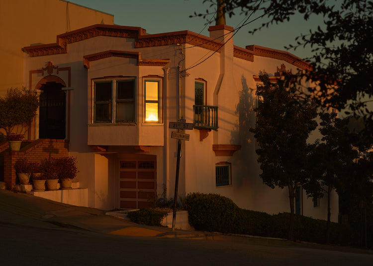 Suburban house laying at an intersection photographed during sunset.