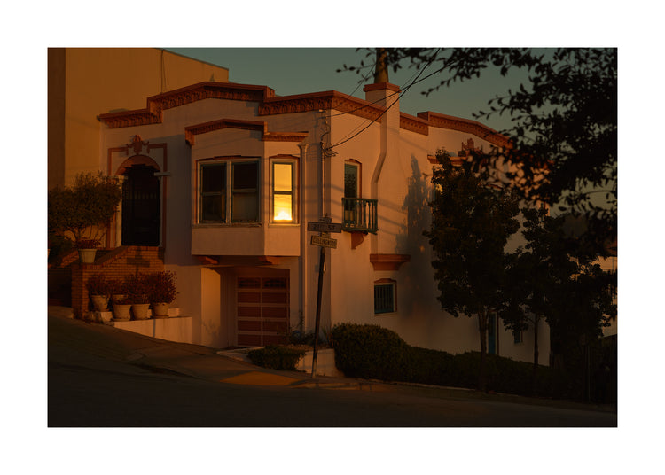 Suburban house laying at an intersection photographed during sunset.