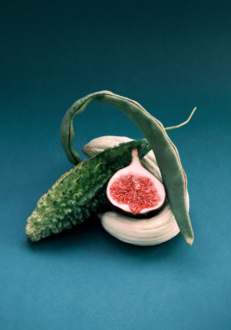 Different fruits and vegetables stacked together on a turquoise canvas.