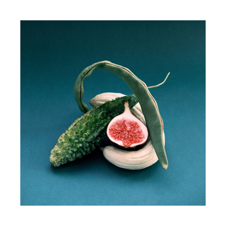 Different fruits and vegetables stacked together on a turquoise canvas.
