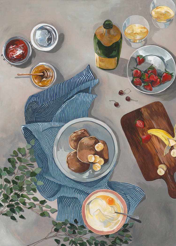 The Breakfast of Champions Poster showcases fluffy pancakes with bananas, yogurt and honey on a striped cloth, cherries beside a board of strawberries and bananas, and bowls of sauces paired with a sparkling champagne bottle.