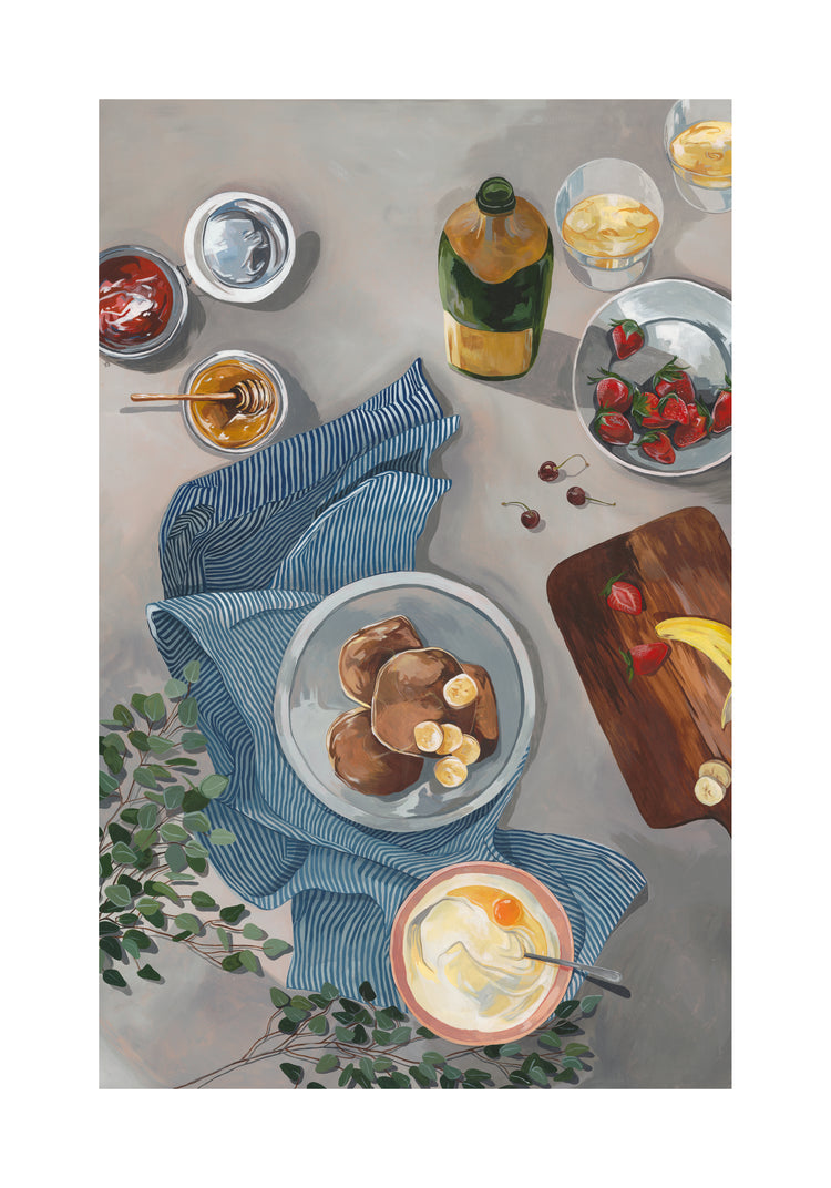 The Breakfast of Champions Poster features fluffy pancakes with bananas, a bowl of strawberries, honey jar, butter dish beside a green bottle, all on a blue-striped cloth. A wooden board with fruit and a glass of juice complete the scene, enhanced by green leaves adorning the table.