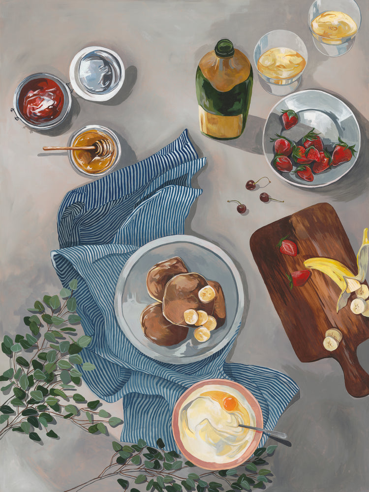 The Breakfast of Champions Poster depicts a breakfast spread with illustrated fluffy pancakes topped with bananas, strawberries, and cherries. Nearby are sliced fruit on a cutting board, yogurt, jam jars, drinks with lemon slices, honey bottles, and a striped cloth for an inviting morning table.