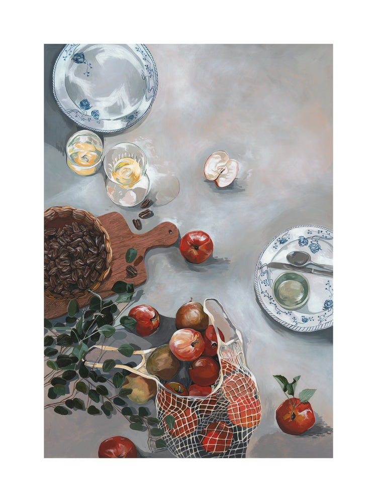 The How Do You Like These Apples Poster features a kitchen table still life with red apples spilling from a net bag, an empty blue and white plate, a wooden bowl of coffee beans, greenery sprigs, and two glasses of water with lemon slices, adding warmth to the decor.