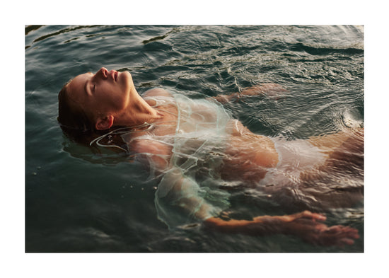 Woman dressed in white floating at the surface of the ocean.