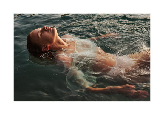 Woman dressed in white floating at the surface of the ocean.