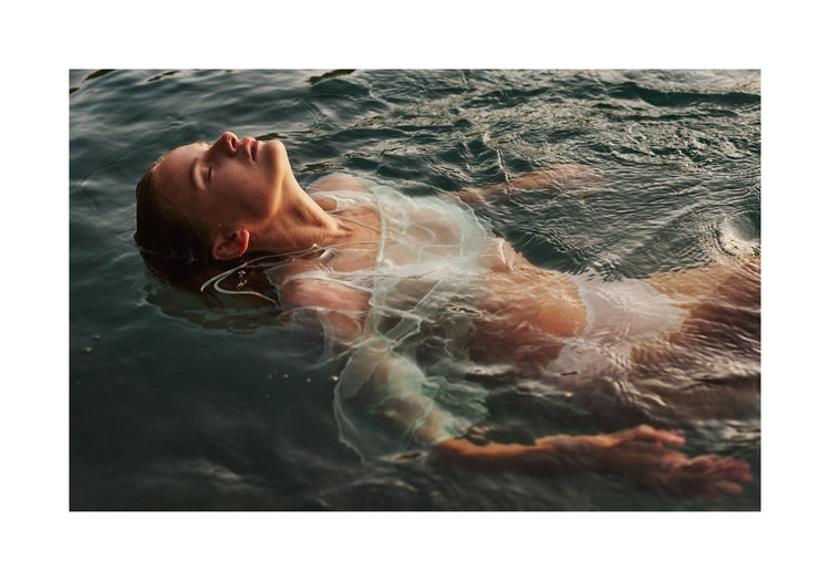 Woman dressed in white floating at the surface of the ocean.