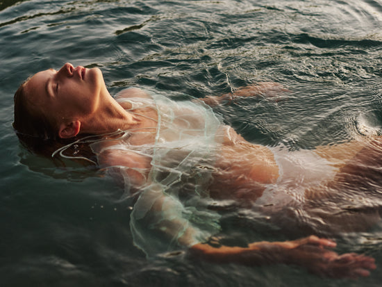 Woman dressed in white floating at the surface of the ocean.