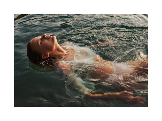 Woman dressed in white floating at the surface of the ocean.