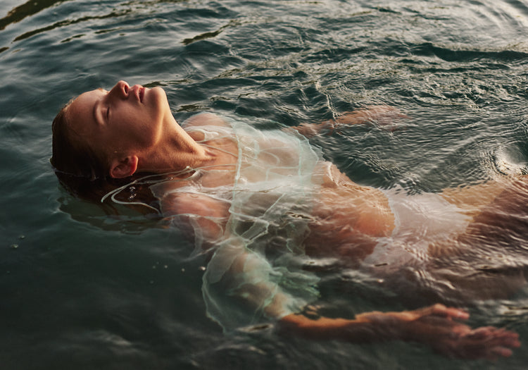 Woman dressed in white floating at the surface of the ocean.