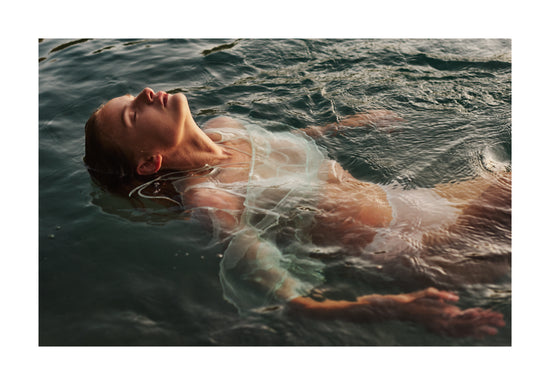 Woman dressed in white floating at the surface of the ocean.