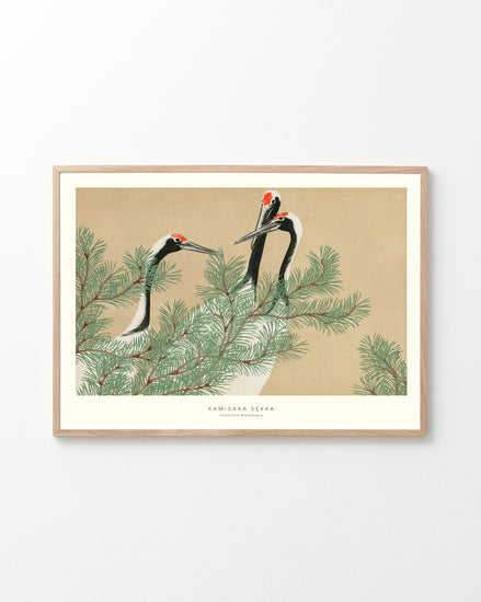 Framed artwork of cranes on a branch with a beige background