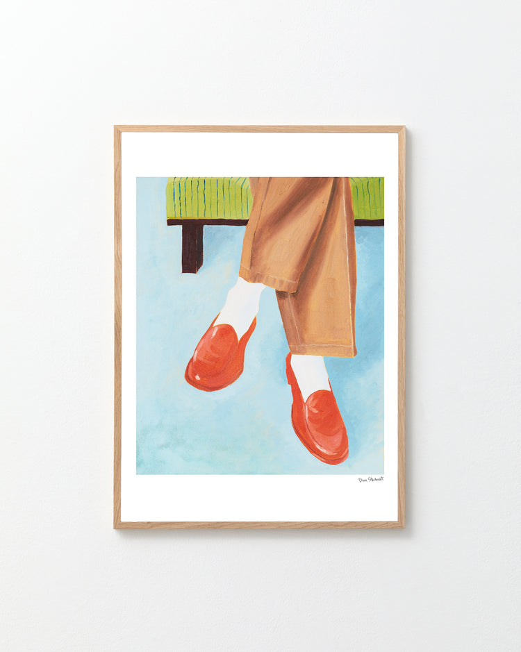 Framed artwork of red shoes, beige pants, and white socks against a blue background.