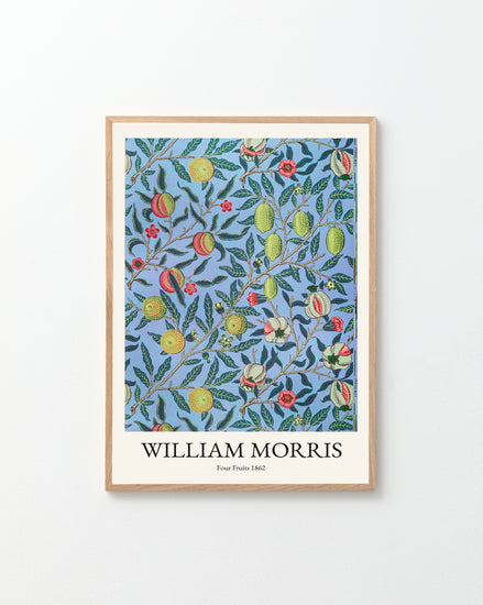 The Four Fruits by William Morris poster exudes classic elegance with its pattern of red and yellow fruit and lush green leaves on a blue background, beautifully displayed in a wooden frame against a white wall.