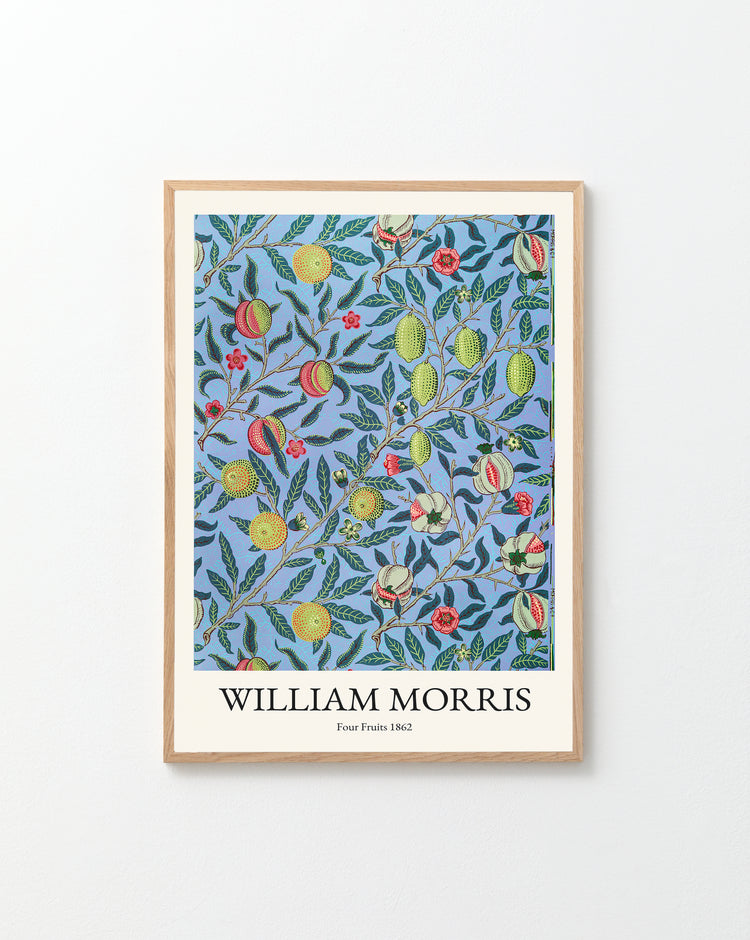 The Four Fruits by William Morris poster exudes classic elegance with its pattern of red and yellow fruit and lush green leaves on a blue background, beautifully displayed in a wooden frame against a white wall.