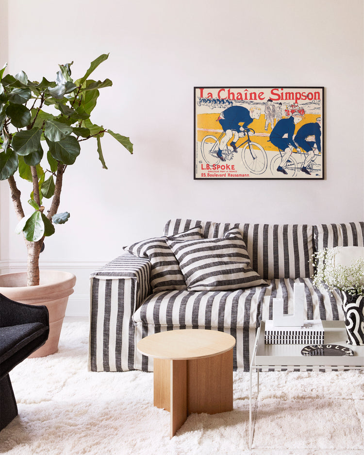Living room with a striped sofa, coffee table, and decorative poster on the wall.